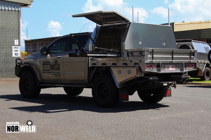 an army truck parked in front of a building with its open hood on it's flatbed