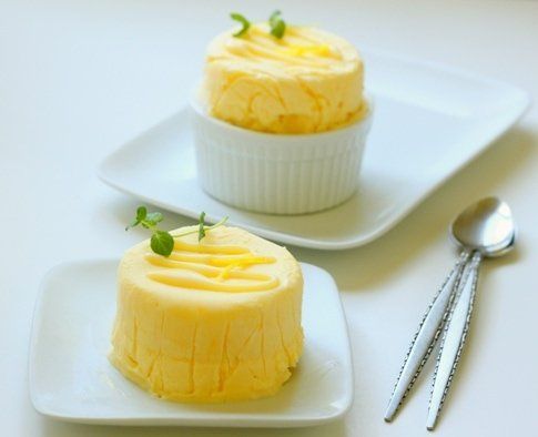 two small desserts on white plates with spoons and utensils next to them