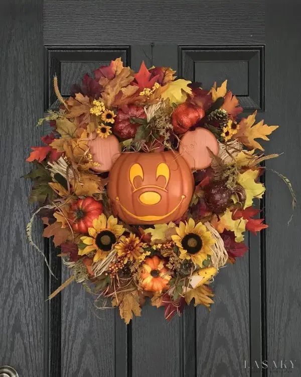 a mickey mouse wreath with pumpkins and autumn leaves