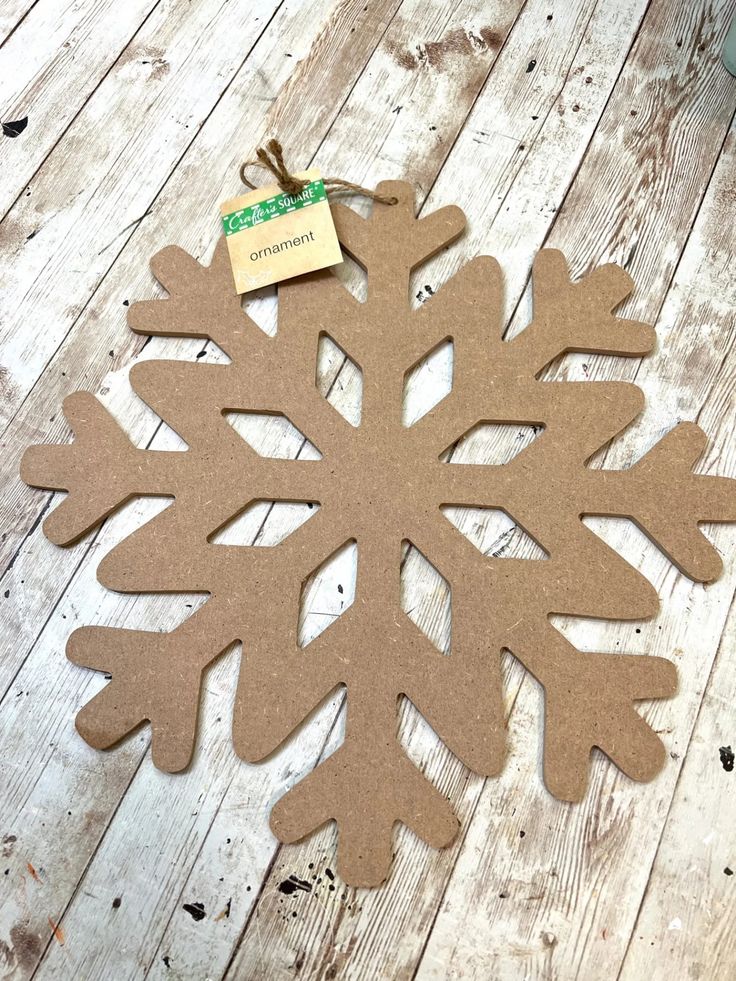 a paper snowflake with a tag on it sitting on a wooden floor next to a potted plant