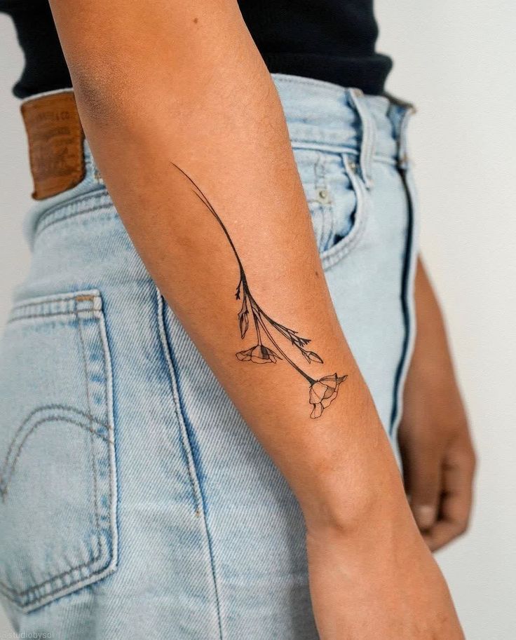 a woman's arm with a tattoo on it and flowers in the back pocket