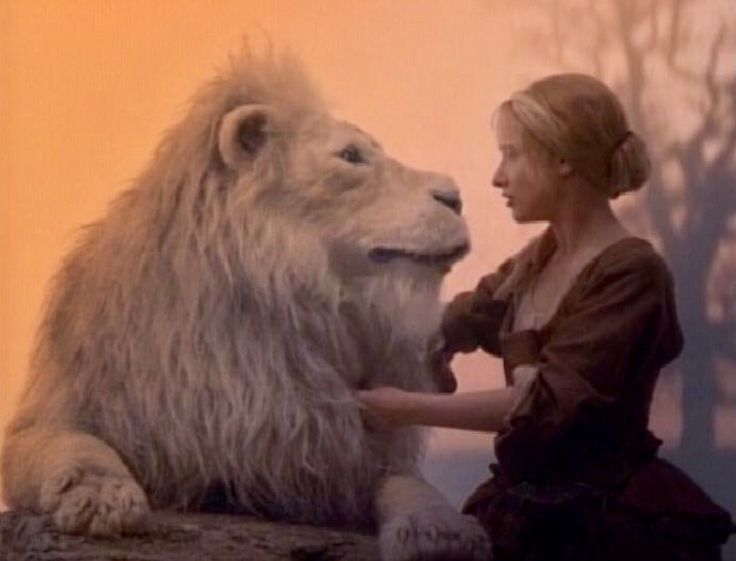 a woman is petting a large white lion