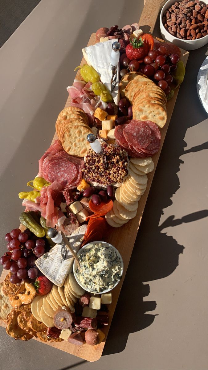 a wooden platter filled with cheese, crackers and meats