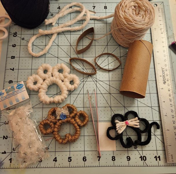 various crafting supplies are laid out on a cutting board with scissors and thread in the foreground