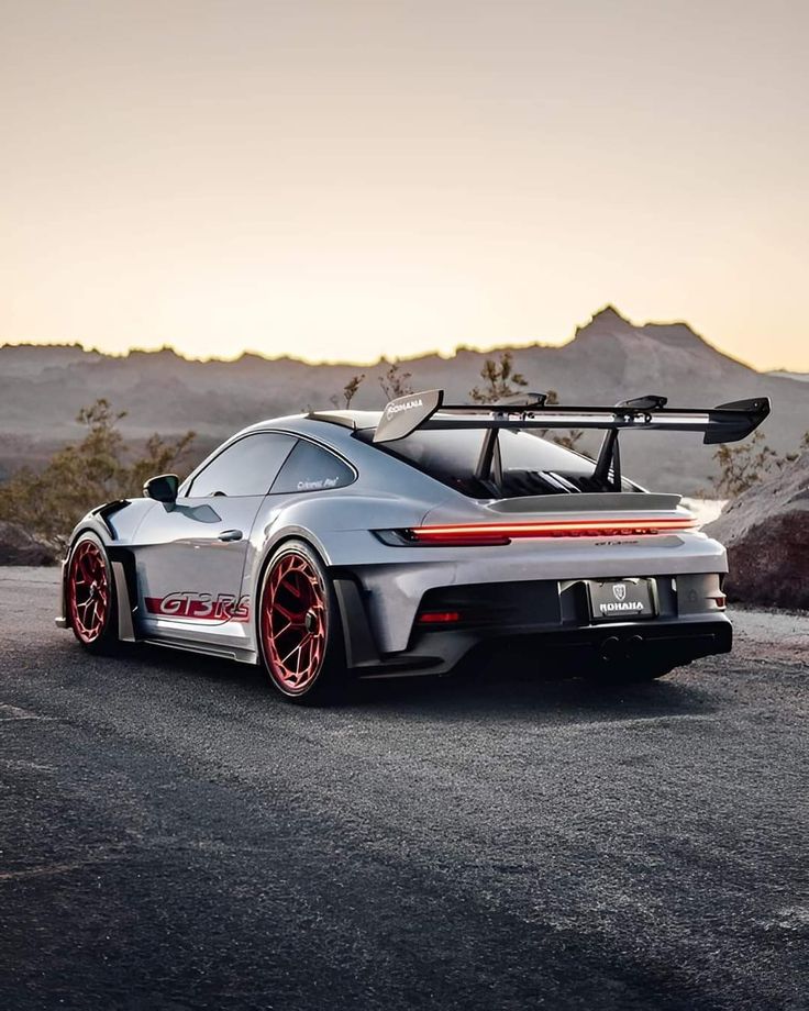 a silver sports car with red rims parked in the desert