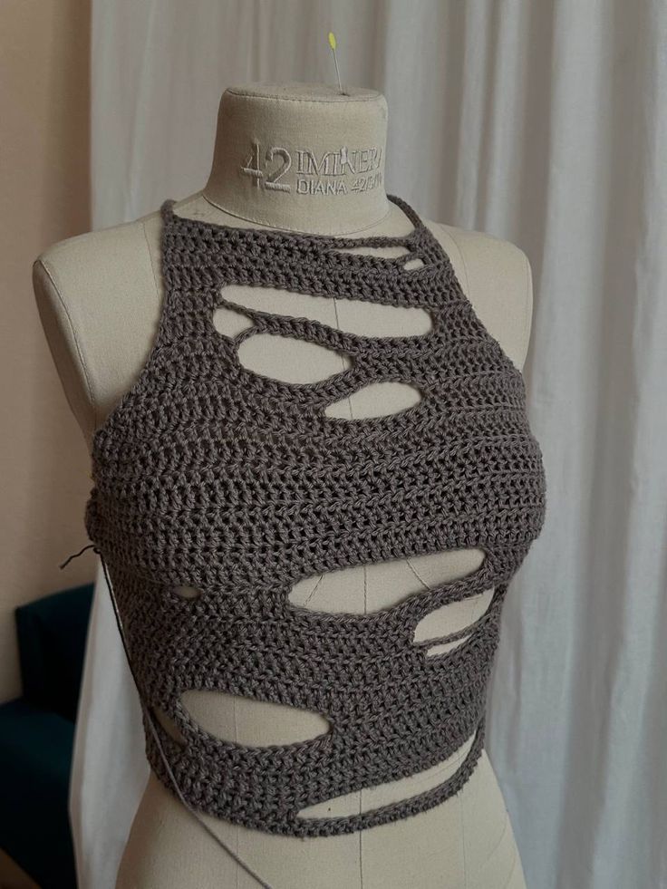 a crocheted top is displayed on a mannequin