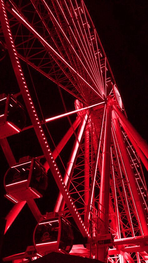 a ferris wheel lit up at night with red lights