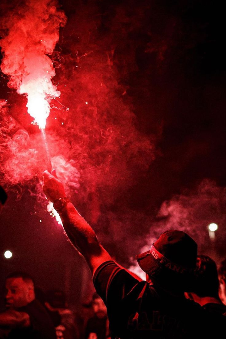 a person holding up a red fire extinguisher in the air at night