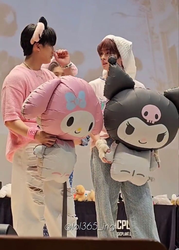 two people standing next to each other with stuffed animals on their backs and one person holding an inflatable teddy bear