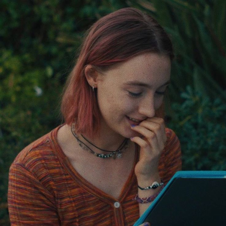 a woman with red hair is looking at an electronic device