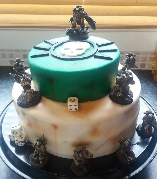 a green and white cake with dices on the top is sitting on a table