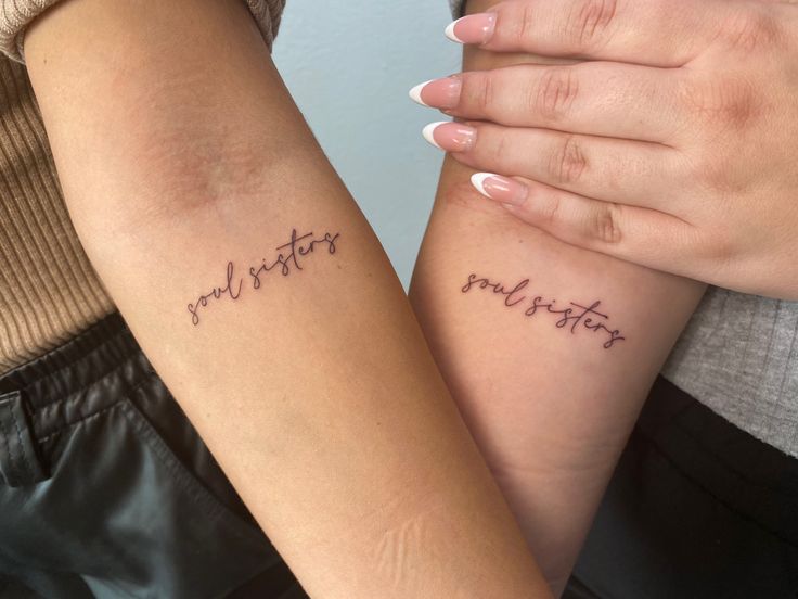 two people with matching tattoos on their arms holding each other's hands and the words mother written in cursive writing