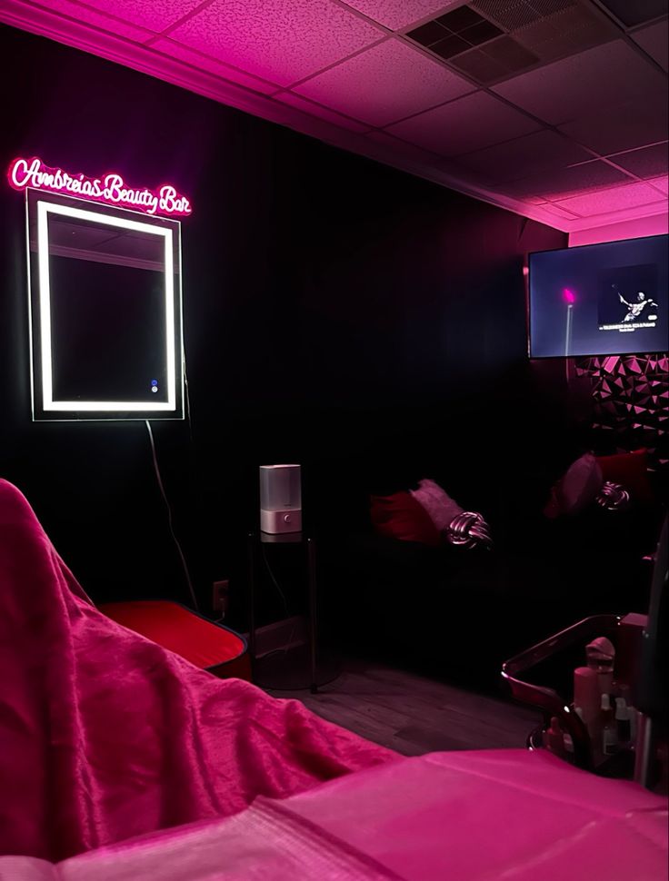 a room with pink lights and a mirror on the wall in front of it that is lit up