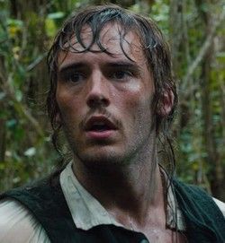 a man with wet hair standing in the woods