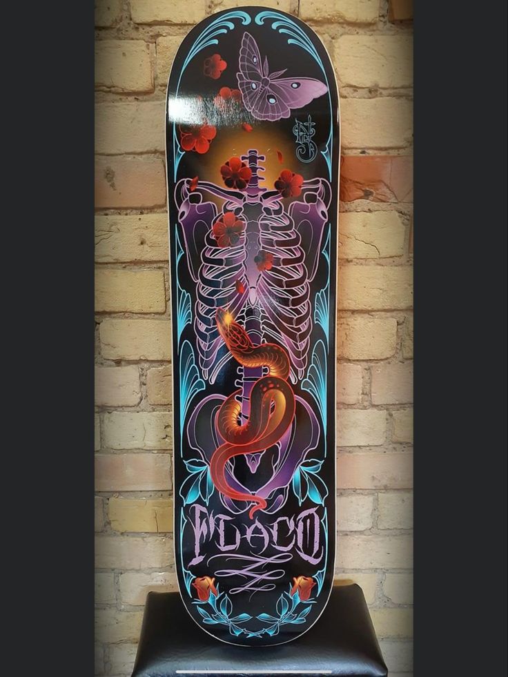 a skateboard with an image of a human skeleton on it's side is displayed in front of a brick wall