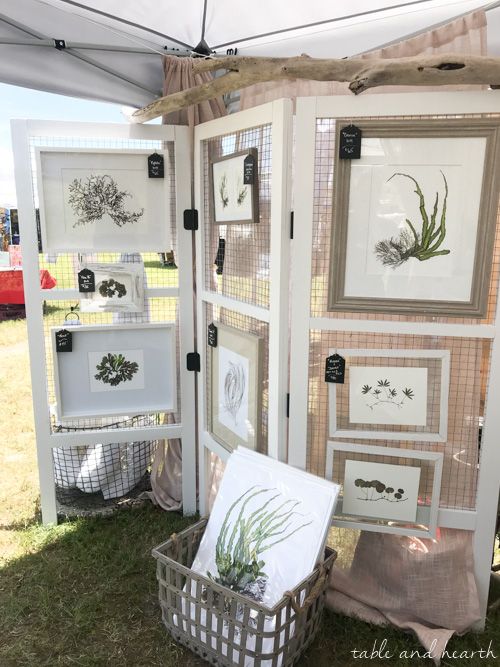 an assortment of framed art on display under a tent