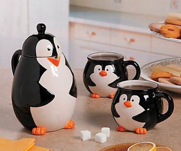 four penguin mugs sitting next to each other on a kitchen counter with orange slices