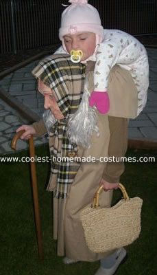 a child dressed up as an old woman with a cane and hat, holding a bag