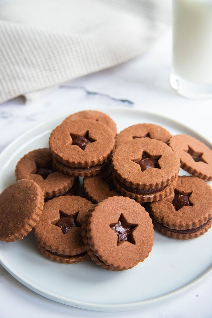 cookies with chocolate filling on a plate next to a glass of milk