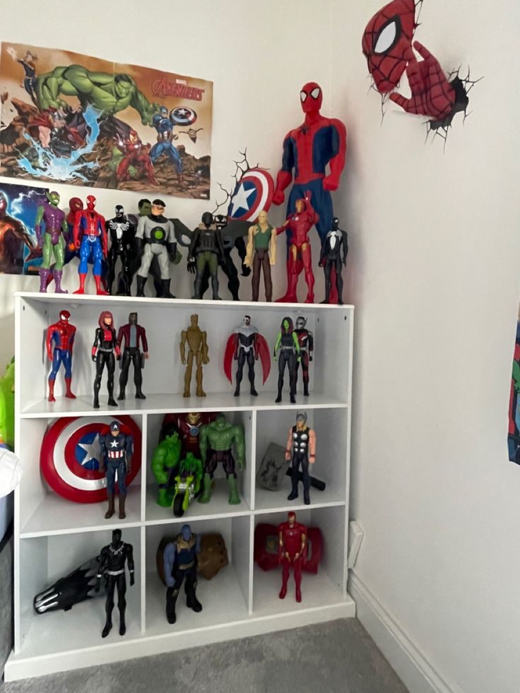 there are many action figures on the shelves in this room, including spider - man and captain america