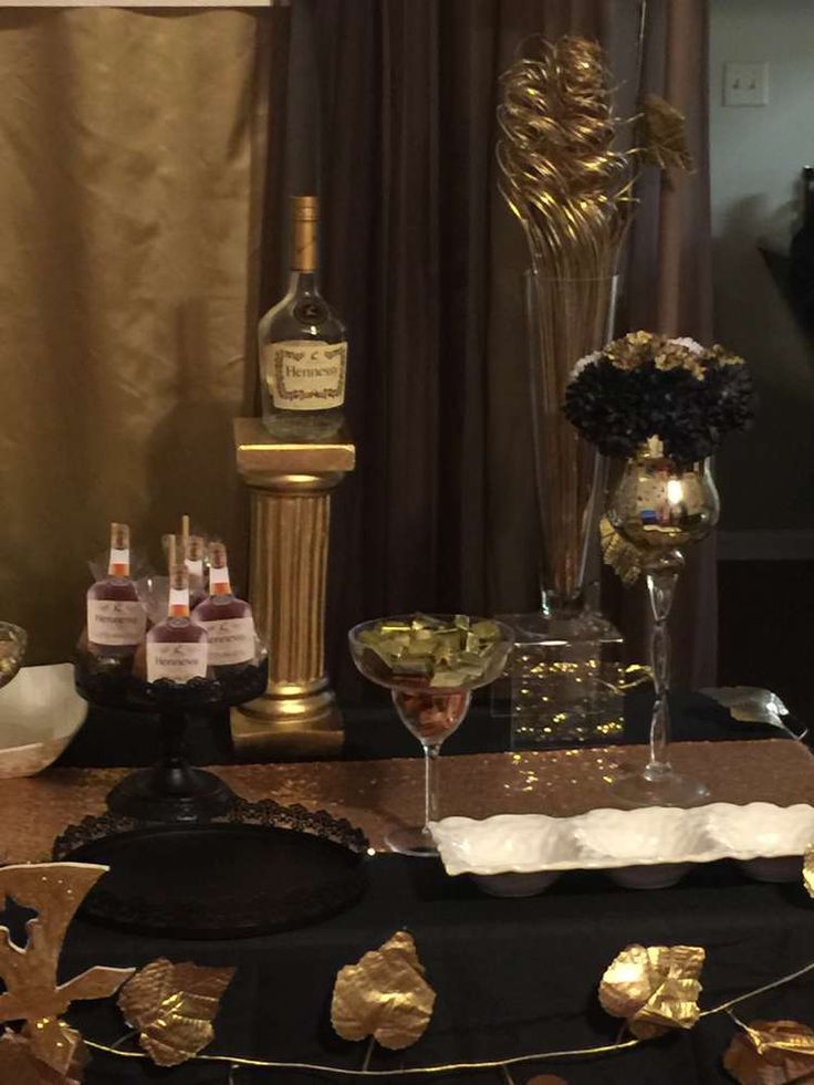 a table topped with lots of bottles of alcohol and gold decorations on top of it