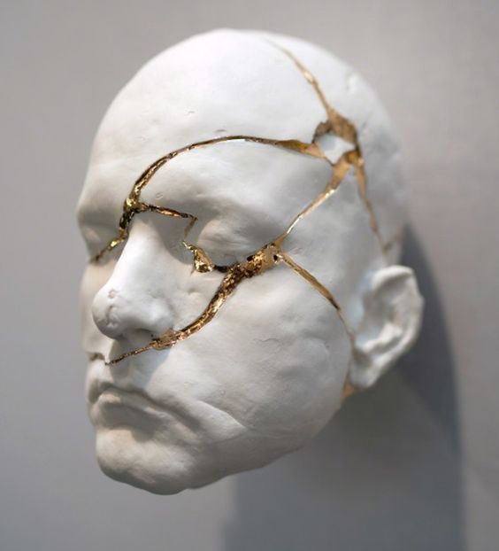 a white mannequin head with gold wire on it's face and neck