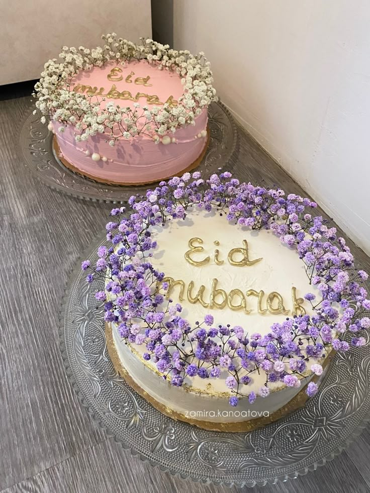 two cakes sitting on top of a table with purple and pink frosted cake toppings