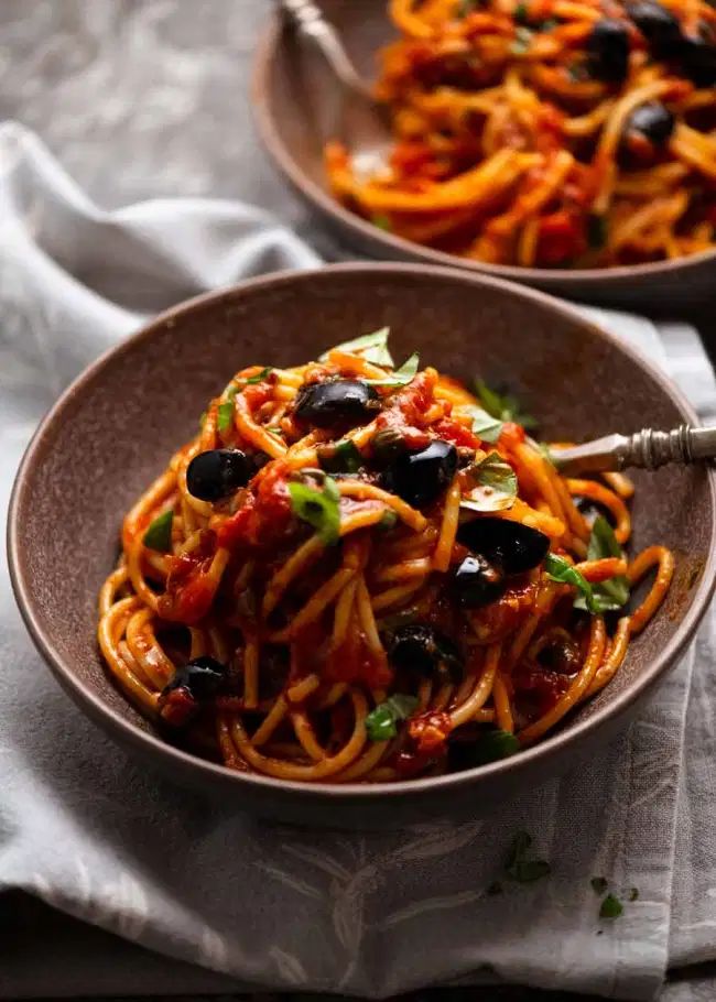 two bowls filled with spaghetti and olives