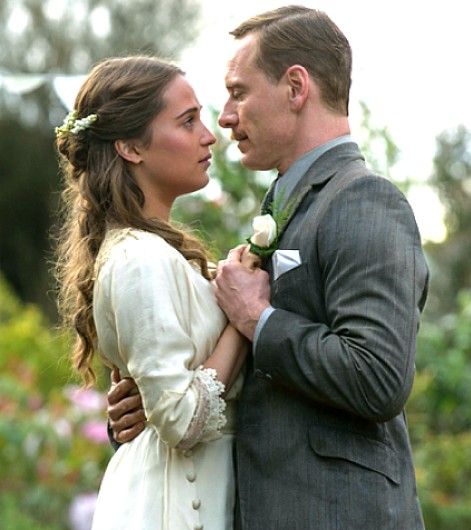 a man and woman standing next to each other with flowers in their hair looking at each other