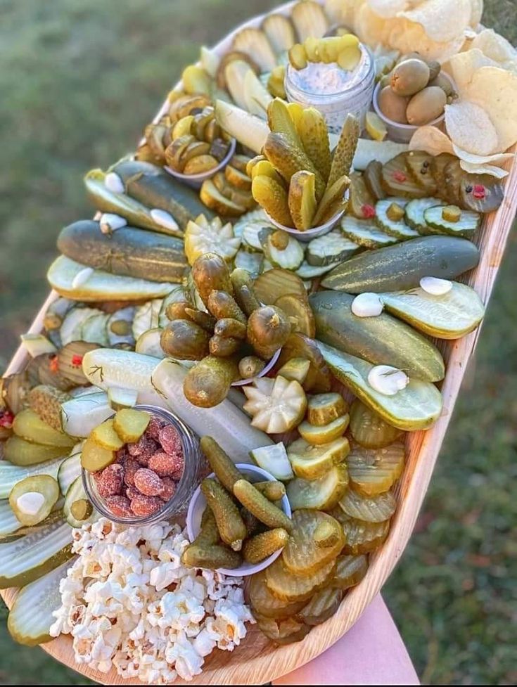 a person holding a wooden boat filled with lots of different types of food on top of it