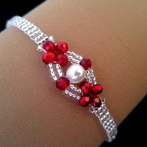 a close up of a bracelet on a woman's arm with red beads and pearls