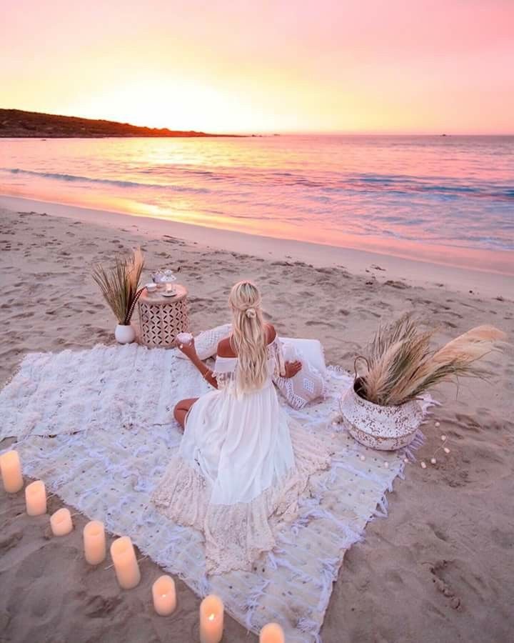 a woman sitting on top of a beach next to candles