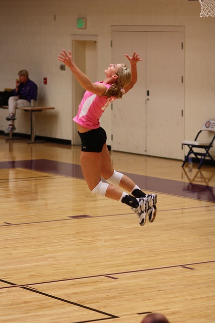 a girl jumping in the air to catch a frisbee on a gym floor