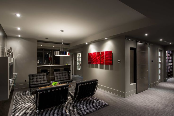 a living room with two black chairs and a red painting on the wall