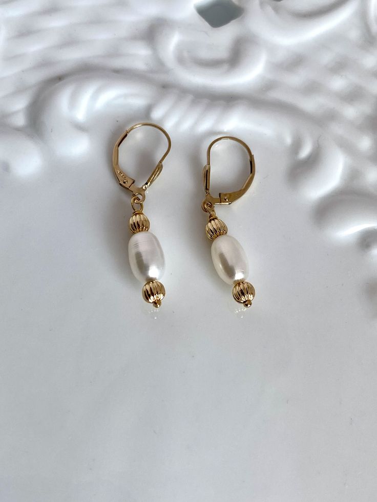 two pearls are hanging from gold - plated earrings