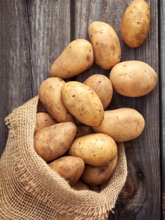 potatoes in a burlock bag on a wooden table