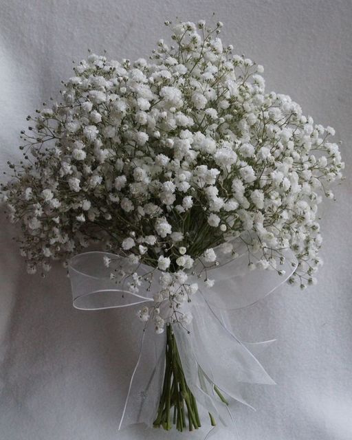 a bouquet of white baby's breath flowers on a white cloth covered tablecloth