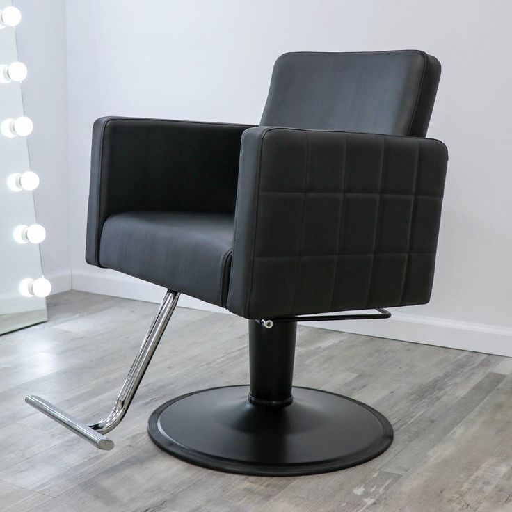 a black chair sitting on top of a hard wood floor next to a white wall