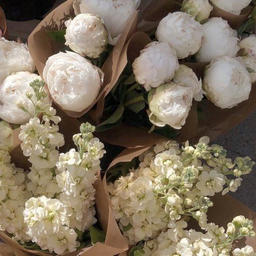 bunches of white flowers sitting on top of brown paper wrapped in brown paper bags