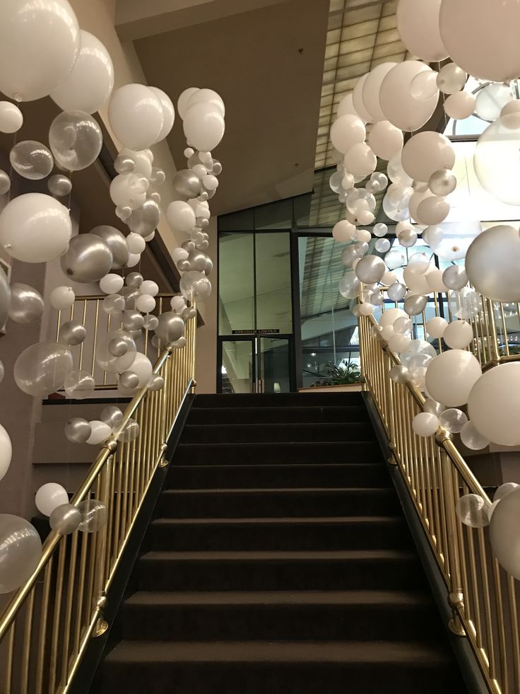 the staircase is decorated with white balloons and streamers