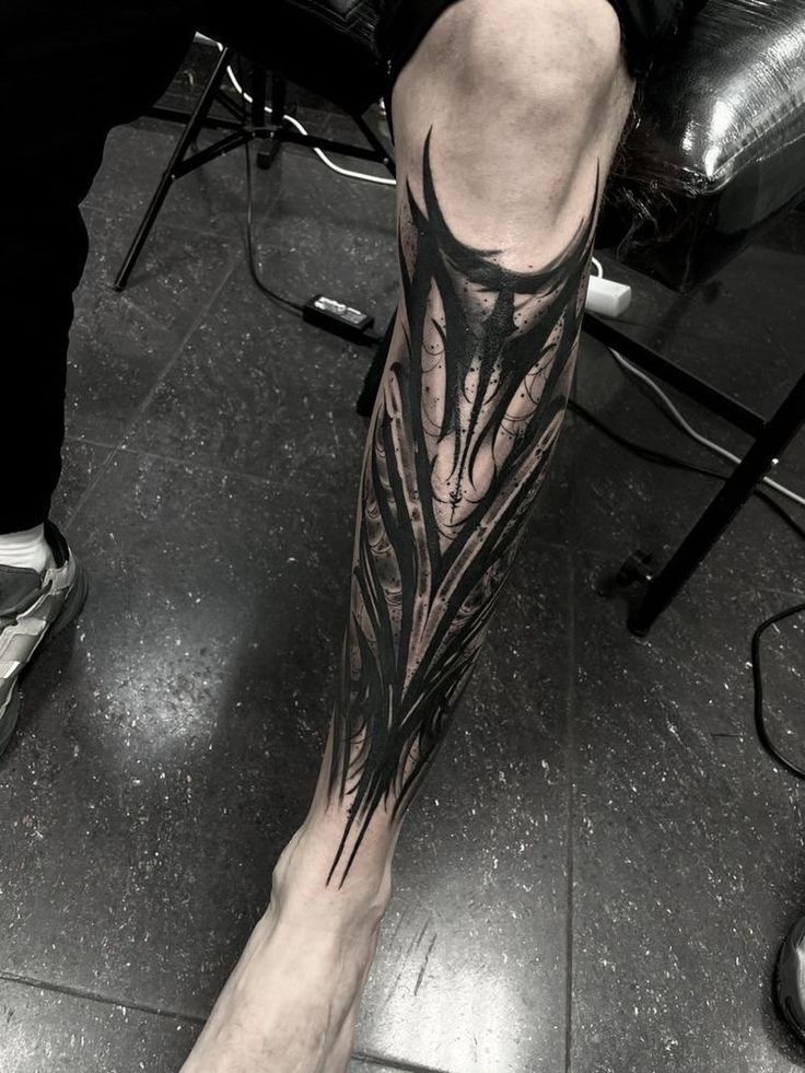 a man's leg with a black and white tattoo design on his left leg