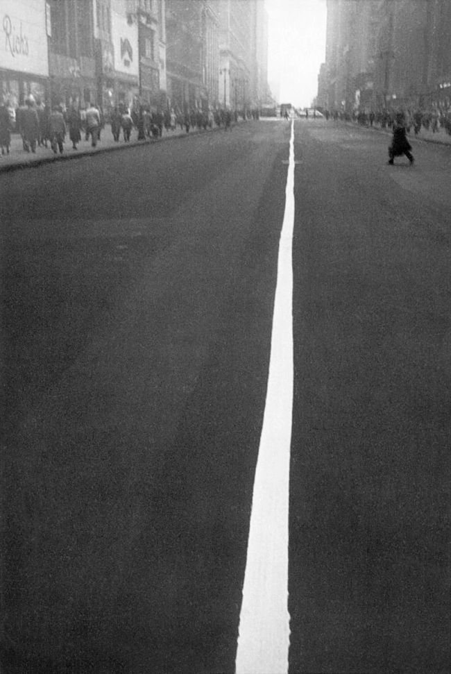 a black and white photo of a person riding a skateboard down a street in the city