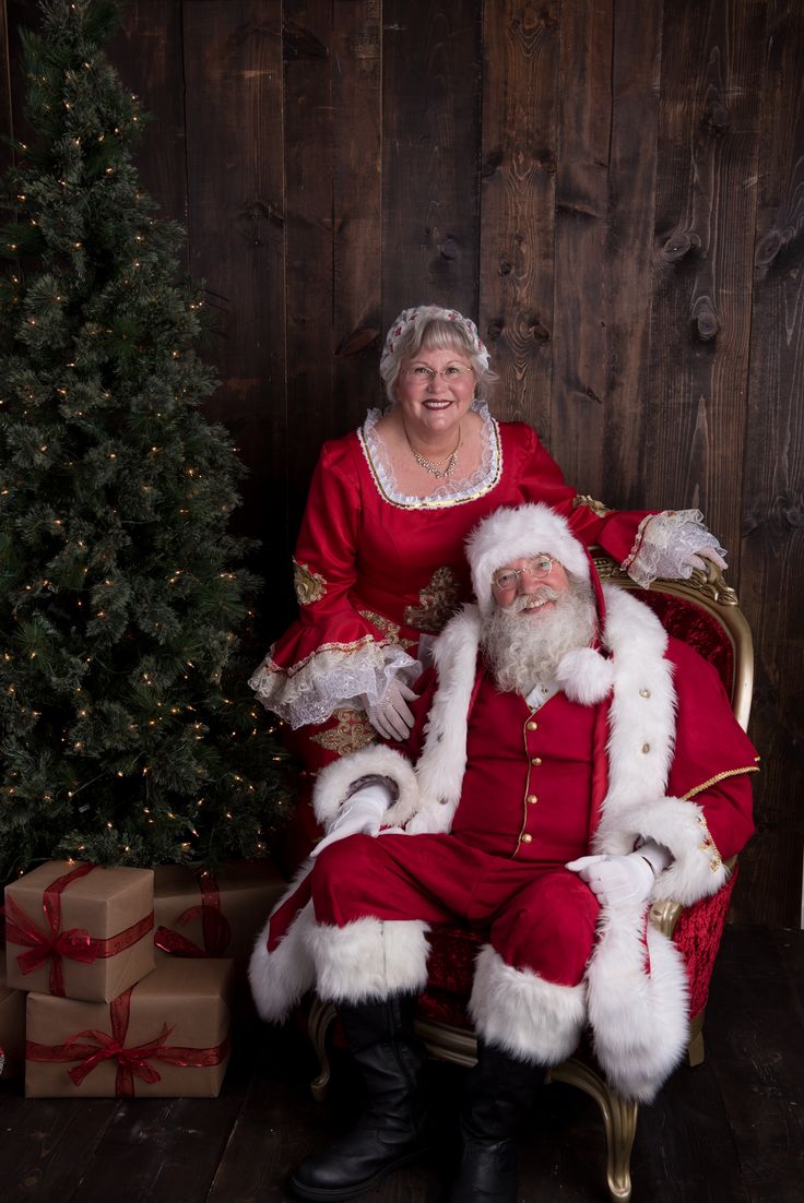 a man dressed as santa claus sitting next to a christmas tree