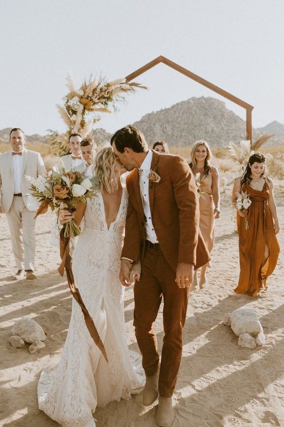 a bride and groom walking down the beach with their bridal party in the background