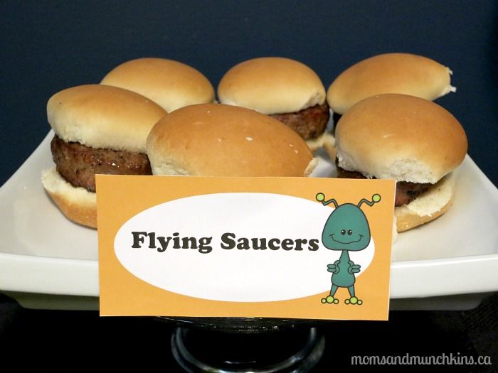 a plate filled with mini hamburgers sitting on top of a white plate next to a sign that says flying saucers