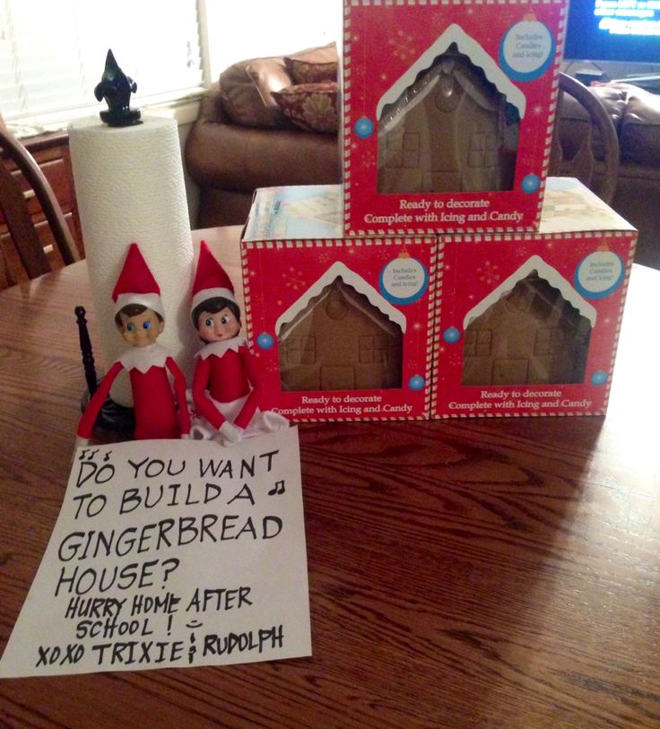 two elfs are sitting on the table next to some gingerbread houses and a sign that says, if you want to build a gingerbread house