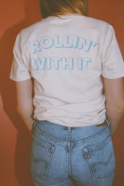 Rollin' With It Tee Light Blue Graphic Print Relaxed Fit T-shirt, Light Blue Graphic Print T-shirt, Light Blue Cotton T-shirt With Graphic Print, Light Wash Crew Neck T-shirt With Letter Print, Light Blue Graphic Print T-shirt With Relaxed Fit, Light Blue Relaxed Fit T-shirt With Text Print, Relaxed Fit Light Blue T-shirt With Text Print, Trendy Light Blue Graphic Print T-shirt, Light Wash Graphic Print Crew Neck T-shirt