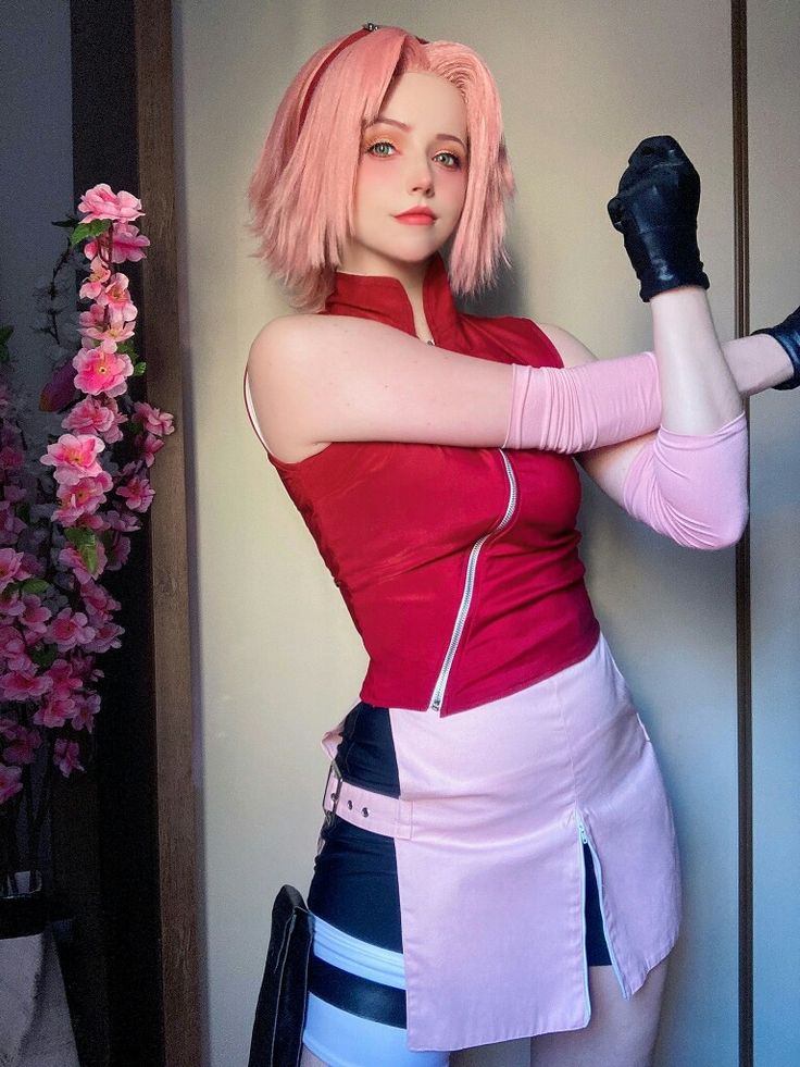 a woman with pink hair and black gloves posing for a photo in front of a wall