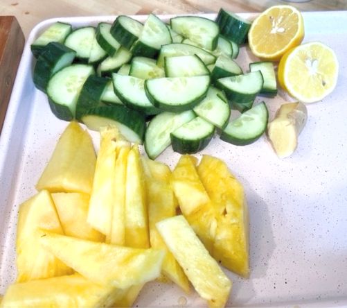 sliced cucumbers and lemons on a cutting board next to some cut up fruit