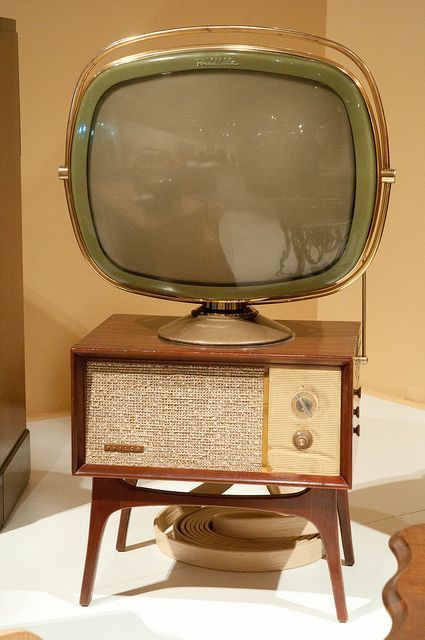 an old fashioned television sitting on top of a wooden stand